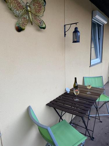 stół z dwoma krzesłami i motylem na ścianie w obiekcie La maison au pays de la nature ,6 couchages w mieście Breginj