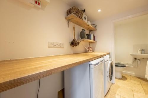 a kitchen with a counter and a washer and dryer at Charnwood Cottage 4 in Burnham Market