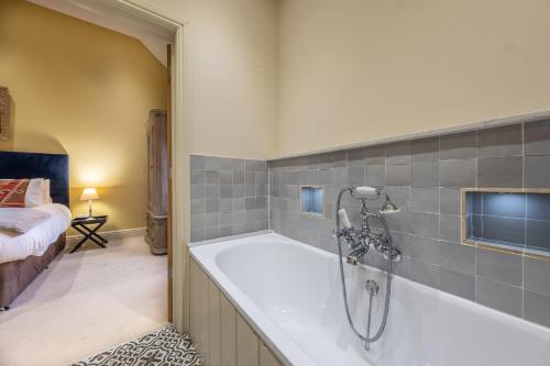 a bathroom with a bath tub and a bedroom at Harnser Barn in Brisley