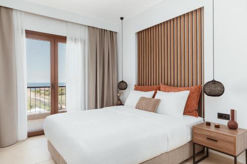 Verano Afytos Hotel في أفيتوس: غرفة نوم بسرير ابيض كبير ونافذة