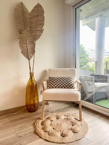 une chaise et une plante dans une pièce avec un vase dans l'établissement Appart avec balcon, parking, plein centre ville - MONT DE MARSAN, à Mont-de-Marsan