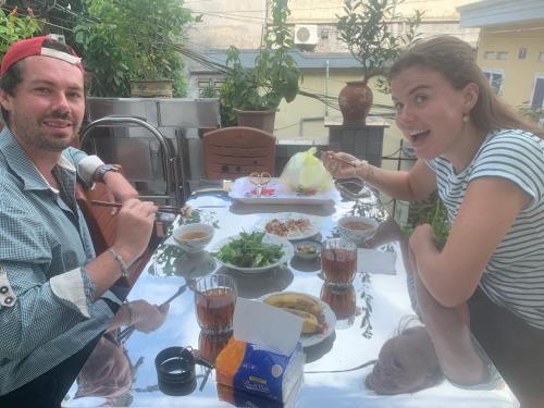 Um homem e uma mulher sentados à mesa com comida. em Rustic Homestay - Phòng nghỉ giá rẻ em Haiphong