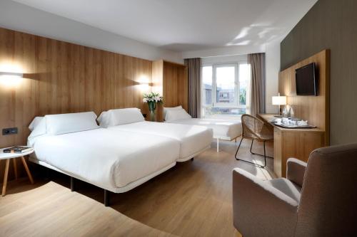 トルトーザにあるHotel SB Corona Tortosaの白い大型ベッドと椅子が備わるホテルルームです。