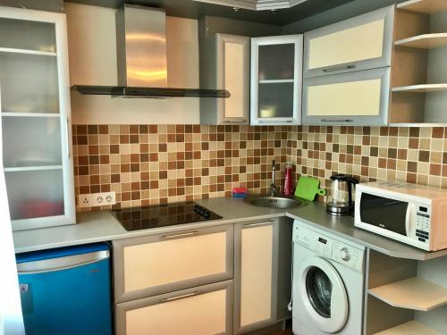 a kitchen with a washer and a microwave at City Center - Nurken Abdirova 32 in Karagandy