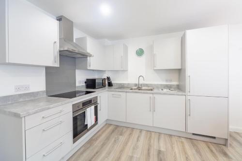 a white kitchen with white cabinets and a sink at Fantastic 2 Bedroom Apartment in Ashford in Ashford