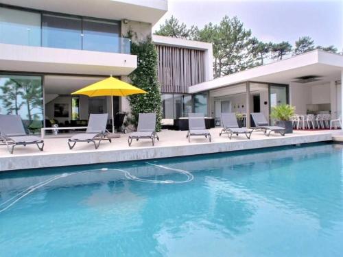 une maison dotée d'une piscine avec des chaises et un parasol dans l'établissement Villa Contemporaine, GOLF AND SEA, Haut de gamme, Vue LAC, à Anglet