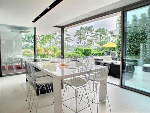 une salle à manger avec une table et des chaises blanches dans l'établissement Villa Contemporaine, GOLF AND SEA, Haut de gamme, Vue LAC, à Anglet