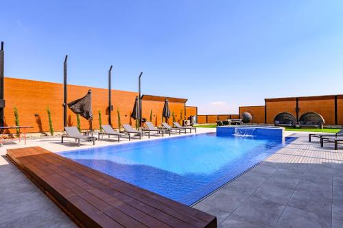 a large swimming pool with chairs and a table at וילה דיימונד בגליל - וילה מושלמת עם בריכה פרטית, ג'קוזי ונוף מהמם in Maghār