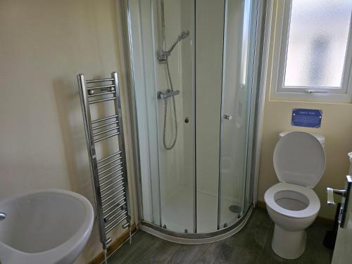 a bathroom with a shower and a toilet and a sink at Castaways Holiday Park in Bacton