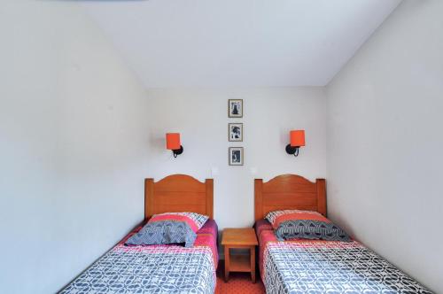 deux lits jumeaux dans une chambre aux murs blancs dans l'établissement La résidence du Lac - maeva Home - Maison 3 pièces 6 personnes - Prestige MAE-0191, à Monflanquin