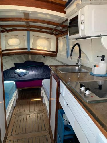 una cocina con fregadero y una cama en una furgoneta en Lovely wooden boat in Port forum, with AC and two bikes., en Barcelona