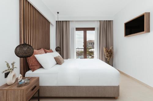 ein Schlafzimmer mit einem großen weißen Bett und einem Fenster in der Unterkunft Verano Afytos Hotel in Afytos