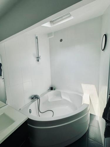 une salle de bain blanche avec une baignoire et un lavabo dans l'établissement Charmant duplex centre ville, à Pantin