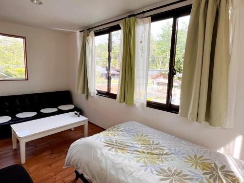 a bedroom with a bed and a couch and windows at Casa Allegra in Yamanakako