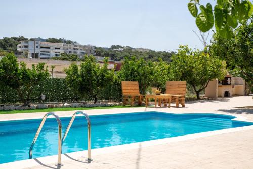 una piscina con 2 sillas y una mesa en Villa Emerald, en Asgourou