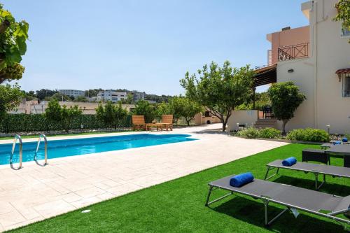 una piscina en un patio con 2 bancos junto a un edificio en Villa Emerald en Asgourou