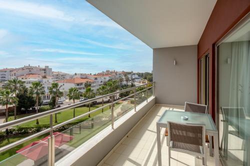 a balcony with a table and chairs and a view of the city at Areias Village Beach Suite Hotel in Albufeira