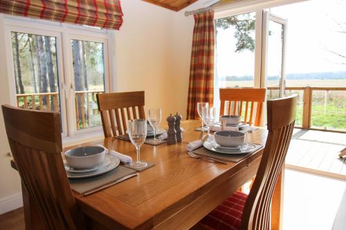 a dining room with a wooden table with chairs and windows at Hollicarrs - Forest Retreat in York