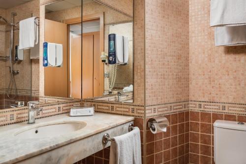 y baño con lavabo, espejo y aseo. en Hotel SB Express Tarragona en Tarragona