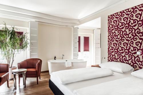 a bedroom with a bed and a bathroom with a tub at Hotel Weitzer Graz - Centre of Graz in Graz