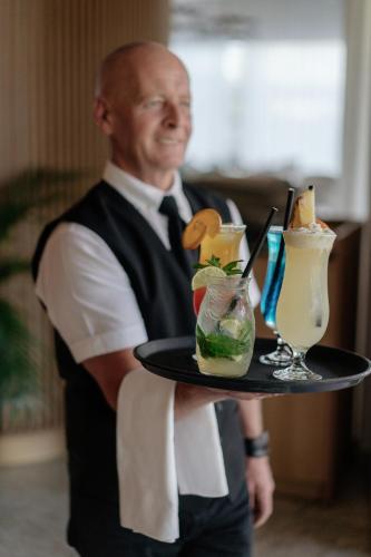 a man holding a tray with some drinks on it at At Herbal Boutique Hotel & Spa in Protaras