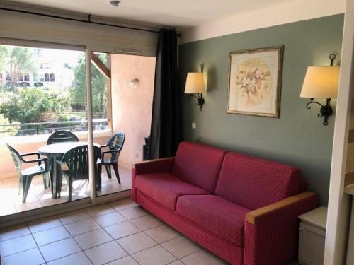 ein Wohnzimmer mit einem roten Sofa und einem Tisch mit Stühlen in der Unterkunft Village Le Rouret - maeva Home - Appartement 2 Pièces 4 Personnes - Sélection MAE-5461 in Grospierres
