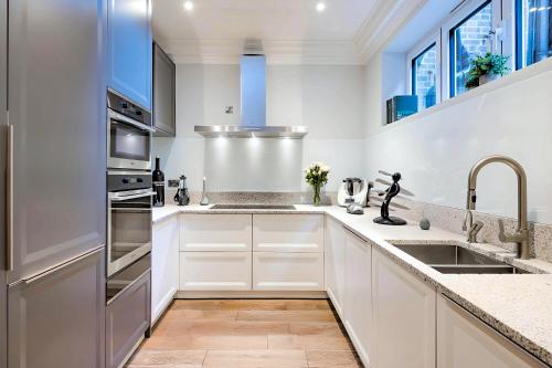 a kitchen with white cabinets and stainless steel appliances at Welcome London - Trafalgar Townhouse in London