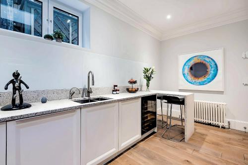 a kitchen with white cabinets and a sink at Welcome London - Trafalgar Townhouse in London