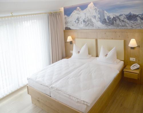 a bedroom with a large white bed with mountains on the wall at Bayrischer Hof in Melle