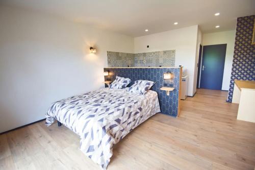a bedroom with a bed with a blue and white comforter at Appartement vue montagnes - MENDIBIL in Zugarramurdi