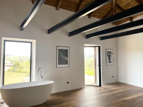 uma grande banheira branca num quarto com janelas em Casa Bianchetti em Costigliole dʼAsti