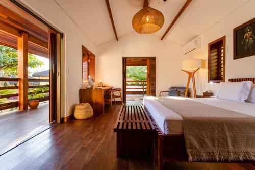 a bedroom with a bed and a desk and a balcony at Aldeia Jericoacoara - Suites Privativas in Jericoacoara