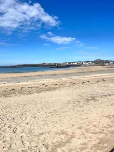 a sandy beach with the ocean in the background at Trearddur Bay ground floor apartment in Trearddur