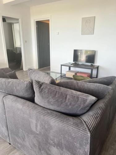 a living room with a gray couch with pillows at Trearddur Bay ground floor apartment in Trearddur