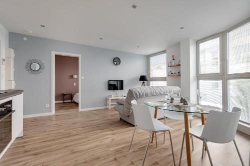 - un salon avec une table en verre et des chaises blanches dans l'établissement Appartement Luce - Welkeys, à Lille