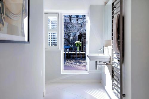 a white bathroom with a window and a sink at Welcome London - Trafalgar Townhouse in London