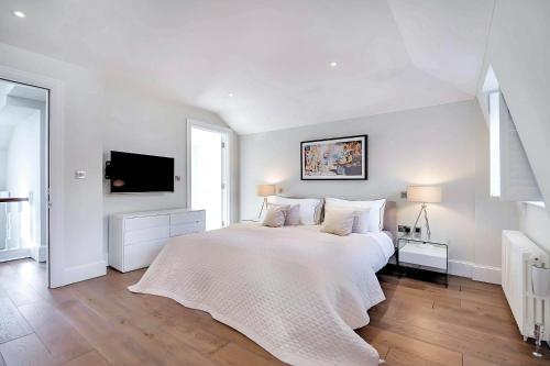 a white bedroom with a large bed and a tv at Welcome London - Trafalgar Townhouse in London