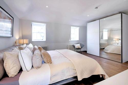a bedroom with a large white bed and a mirror at Welcome London - Trafalgar Townhouse in London