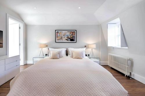 a white bedroom with a large bed with two pillows at Welcome London - Trafalgar Townhouse in London