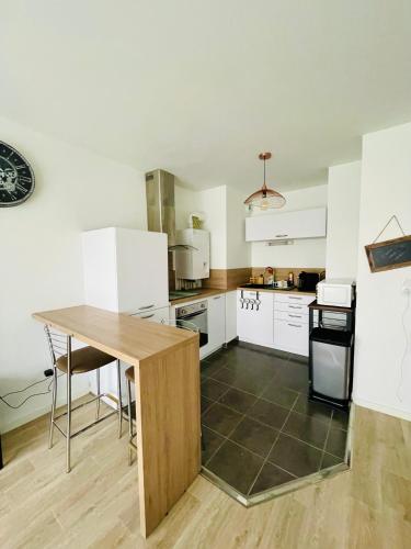 une cuisine avec des armoires blanches et une table en bois dans l'établissement Chez André - Appartement 4 personnes prox Lille, à Saint-André