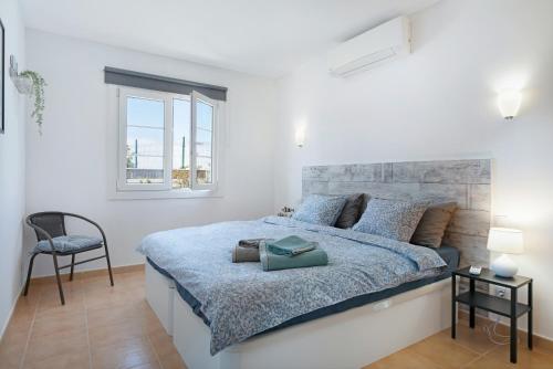biała sypialnia z dużym łóżkiem i krzesłem w obiekcie Mi Casita w mieście Playa Blanca