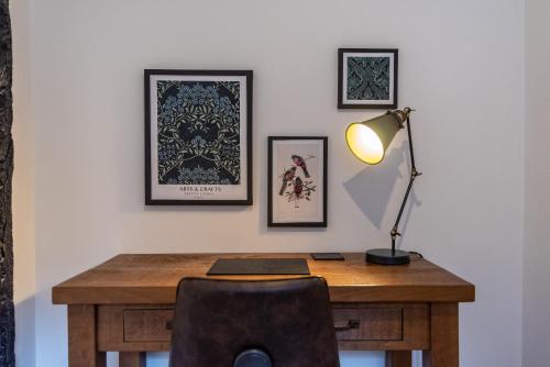 een bureau met een lamp en ingelijste foto's aan een muur bij Blackfriars House, overlooking Chester Racecourse in Chester