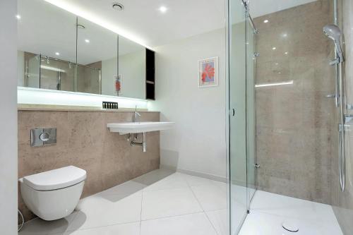 a bathroom with a toilet and a glass shower at Welcome London - Trafalgar Townhouse in London