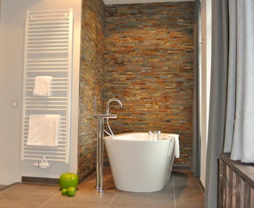 a bath tub in a bathroom with a brick wall at StrandBerg's Designhotel Viktoria in Braunlage