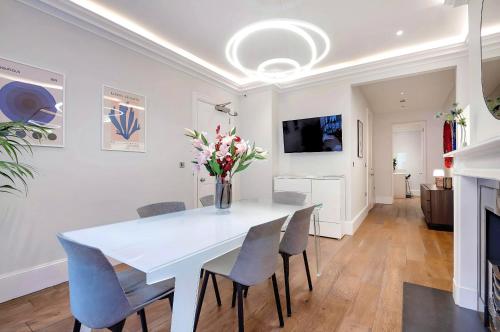 a white dining room with a white table and chairs at Welcome London - Trafalgar Townhouse in London