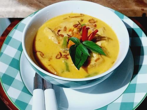 a bowl of soup on a plate on a table at Raturinjani homestay in Selong