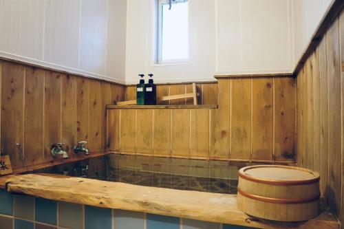 a bathroom with a wooden tub and a toilet at IG2 源泉掛け流し温泉付きの宇佐美貸切宿 お宿 喜喜哀楽 Oyado Kikiairaku in Ito