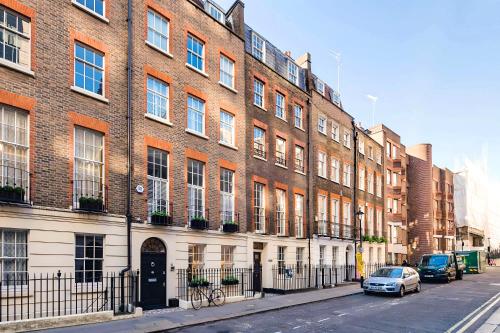 a large brick building with cars parked in front of it at Welcome London - Trafalgar Townhouse in London