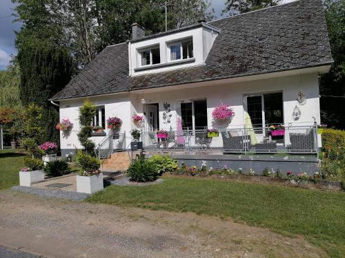 une maison blanche avec des fleurs sur la terrasse couverte dans l'établissement Chez Fabiola et Alain, à Signy-le-Petit