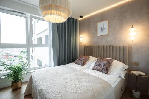a bedroom with a white bed and a large window at KOBIELA APARTMENTS Dębowe Tarasy in Katowice